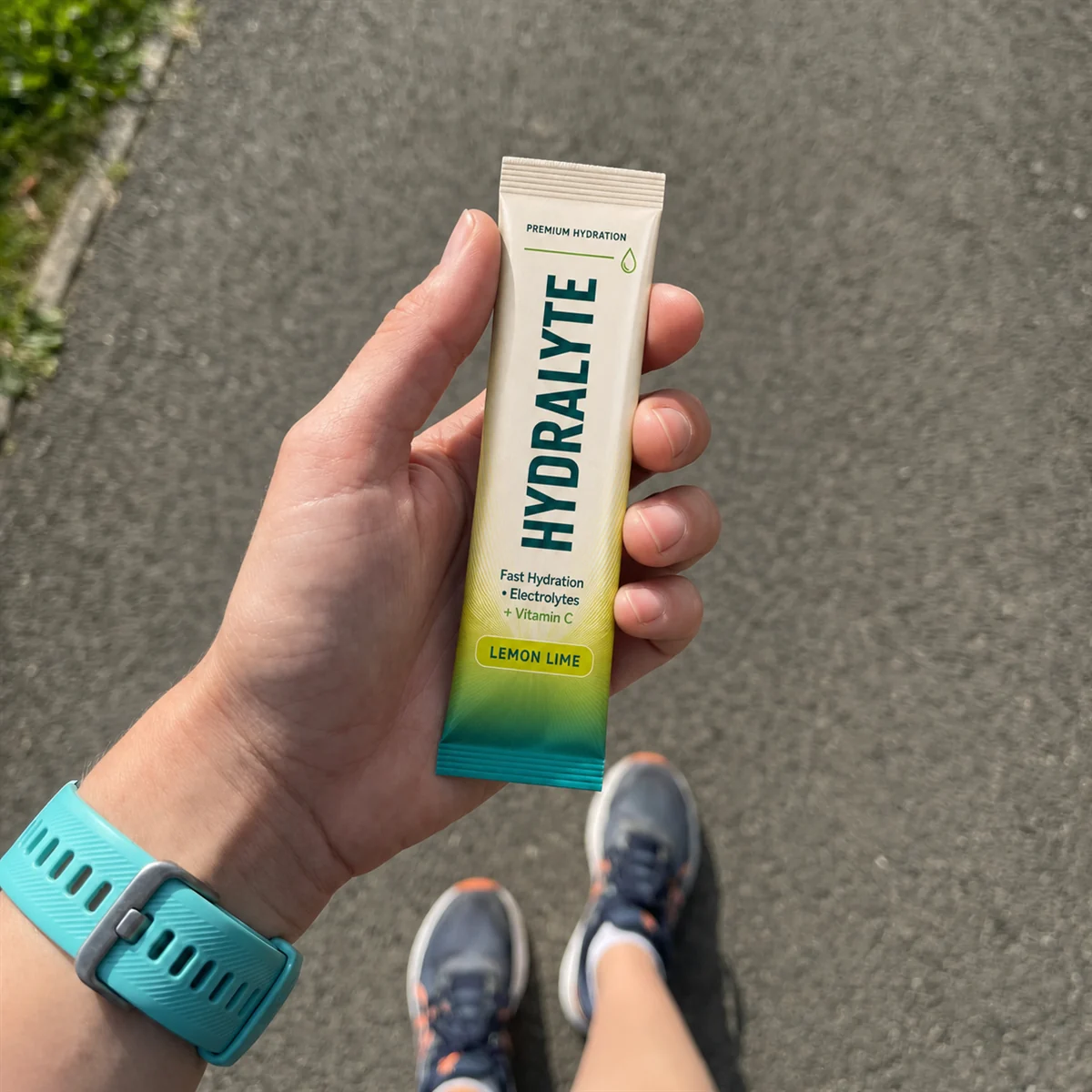 Runner in the UAE holding a Hydralyte Lemon Lime electrolyte stick sachet over a sunlit path